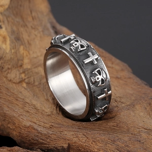 Detail of retro punk cross and skull rotating ring on a textured dark wood background