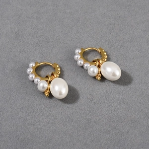 Detailed macro view of gold hoops with removable large white oval pendant pearls