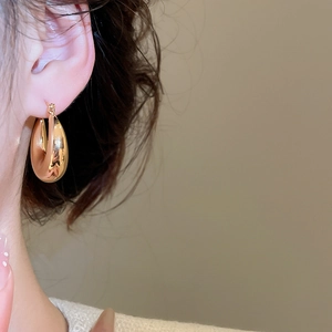 Gros plan de boucles d'oreilles créoles dorées en forme de goutte au fini poli miroir