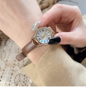 Close-up of rose gold watch with brown leather strap and shimmering seashell dial