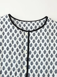 Detailed close-up of quilted floral jacket with blue leaf pattern and black piping details