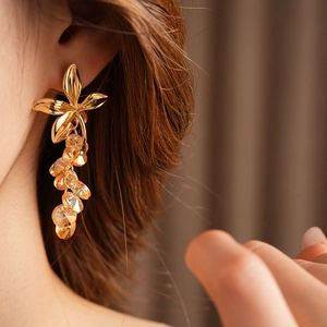 Detail of vintage flower tassel earrings with orange crystal beads on a model