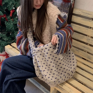 Detail of plush beige tote bag with blue star patterns shown in a cozy outdoor setting