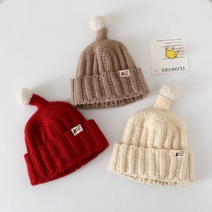 Three assorted knitted children beanies in red brown and beige with white pompom accents