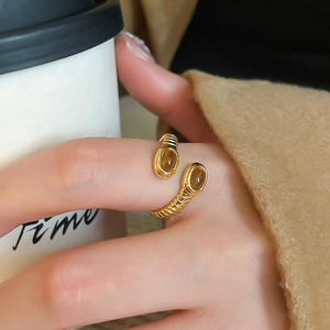 Detailed close-up of a vintage-style gold ring with oval tiger eye stones on fingers