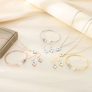 Flat lay of Fatima Hand jewelry set in gold, silver, and rose gold on silk fabric