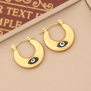 Golden crescent moon earrings with evil eye enamel inlay on a textured jewelry tray