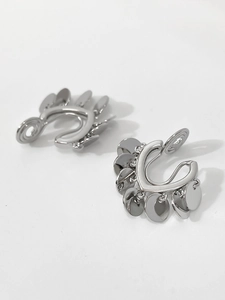 Detail of silver U-shaped clip-on earrings with metallic sequin tassels and minimal design