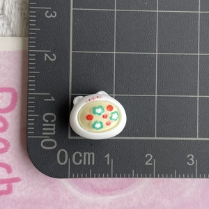 Macro shot of a mini cat resin dessert charm with floral pattern on a scale mat