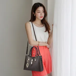 Fashionable dark brown tote bag for women with leaf pendant worn by a model