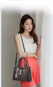 Fashionable dark brown tote bag for women with leaf pendant worn by a model