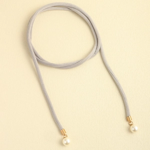 Detail of gray velvet lariat belt with gold metal tips and glossy white pearls
