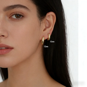 Detail of s925 silver 10mm and 12mm gold hoop earrings shown worn on the model's ear