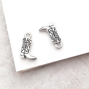 Macro shot of vintage silver western boot pendant charm with a detailed metallic texture