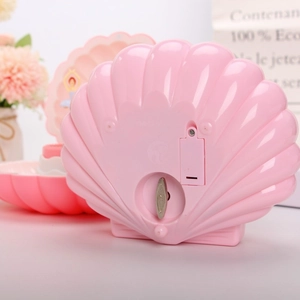 Detail view of the mechanical wind-up key and battery compartment of pink shell music box