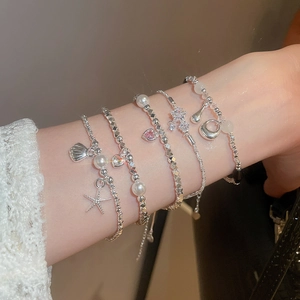 Dettaglio di un bracciale argento multistrato con stella marina, perle e cuore rosa