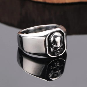 Macro shot of silver punk skull ring with detailed relief on polished wood surface