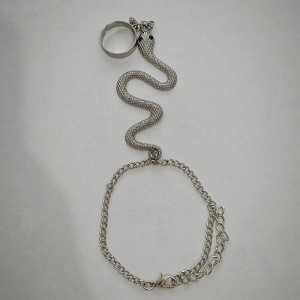 Dettaglio del bracciale ad anello a serpente argentato con trame a scaglie e pietre nere