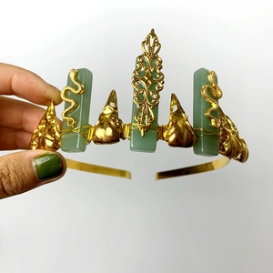 Golden crown headband featuring green crystal pillars with snake and crow skull accents