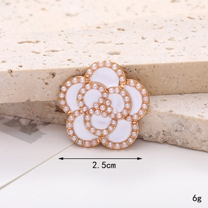 Detail of a 2.5cm white enamel camellia shoe charm with faux pearls and gold metal base