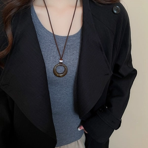 Detail of dark brown ring pendant with coffee braided rope on a minimalist outfit