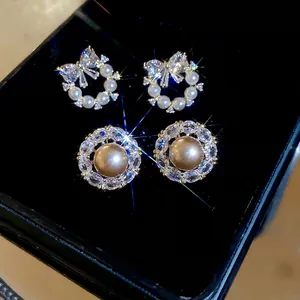 Elegant bow and sunburst pearl stud earring set with zircons in a black jewelry box