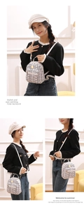 Detail of a mini women's backpack with gray snakeskin texture and metal zipper accents