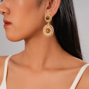 Vintage gold hollow sunburst earrings with tiger eye stone worn by a model