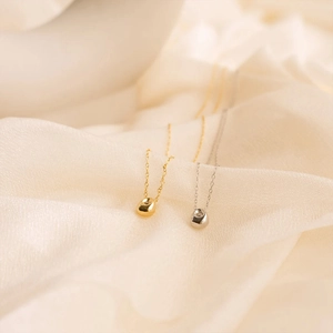 Macro shot of gold and silver bean-shaped pendants on elegant white pleated fabric