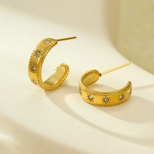 Detail of 18K gold-plated C-shaped earrings with micro-set zircons and sunburst carvings