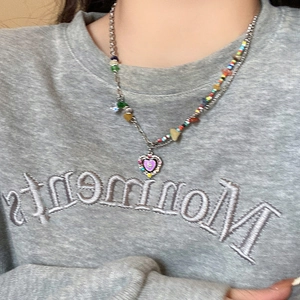 Detail of a layered Y2K necklace with colorful beads and a metal heart charm