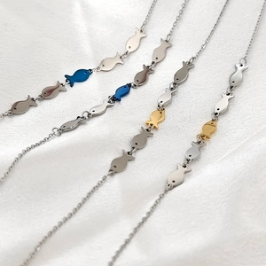 Detailed macro view of small fish charms on delicate chains in gold, blue, and silver finish