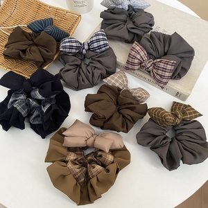 Detailed macro view of assorted earth-tone plaid and solid fabric bow scrunchies