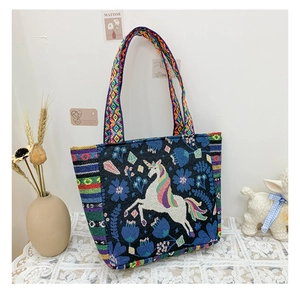 Close-up of ethnic style tote bag featuring colorful unicorn embroidery and rainbow strap