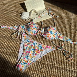 Bikini-Set mit Blumenmuster, Bügel-Top und seitlich gebundenem Höschen auf Matte