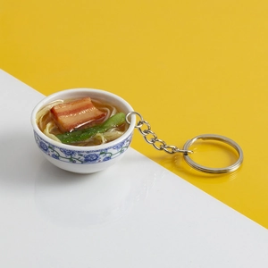 Dettaglio di un portachiavi in miniatura con ciotola di noodle e maiale brasato decorata