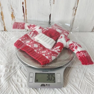 Kitchen scale weighing a red and white knitted Christmas sweater wine bottle cover at 30.5g