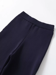 Detail of high-waist elastic waistband on dark blue ribbed knit trousers for women