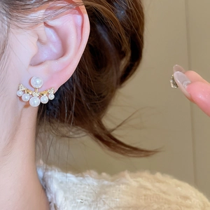 Close-up of elegant gold fan-shaped pearl earrings worn by a model for a chic style