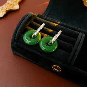 Vue macro de boucles d'oreilles en jade vert et diamants argentés dans leur écrin