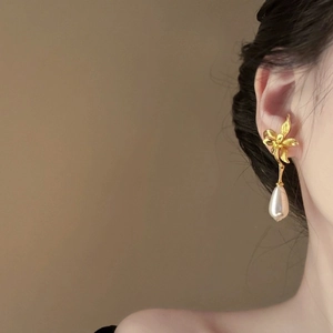 Boucles d'oreilles fleur dorée avec perles pendantes sur mannequin en gros plan d'oreille