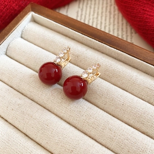 Detail view of red zircon earrings on velvet box with elegant gold metal craftsmanship