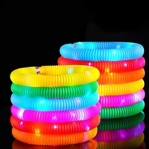Close-up of glowing colorful LED pop tubes in yellow green and pink on reflective surface