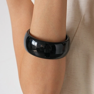 Detail view of thick black acrylic geometric bangle with a high-polish mirror finish