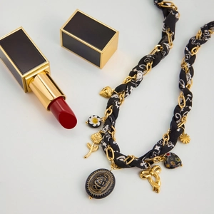 Détail du collier chaîne tressé avec tissu floral et breloques de rose noire