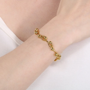 Detailed view of a gold-plated wavy ball chain bracelet worn on a female wrist