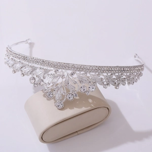 Elegant silver bridal tiara with sparkling floral rhinestones on a beige display pillow