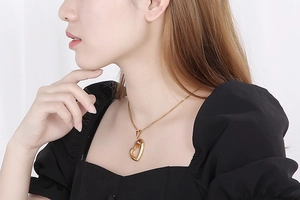 Close-up of a stylish gold hollow heart-shaped pendant necklace worn by a model