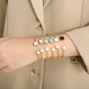 Dettaglio di bracciali rigidi in acciaio inossidabile con zirconi quadrati colorati indossati