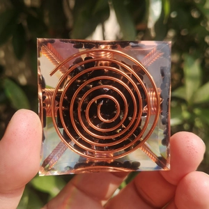 Handcrafted orgonite pyramid with black crystal gravel and spiral copper coil in resin
